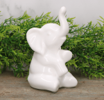 Słoń "siedzący okrakiem" szkliwiony biały 14cm 